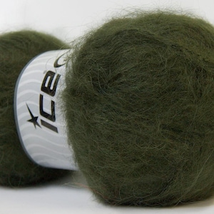 May include: Close-up of a skein of olive green yarn. The yarn is fluffy and soft, with a slight sheen. A white label with the word "ICE" and a star is visible on the yarn.