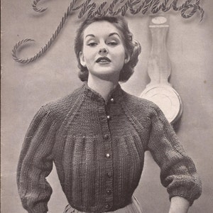 May include: A black and white photo of a woman wearing a gray knitted cardigan with buttons. The cardigan has a round neckline and long sleeves. The woman is standing in front of a wall with a clock on it. The text "Jiffy Tricot" is written in a decorative font at the top of the image.