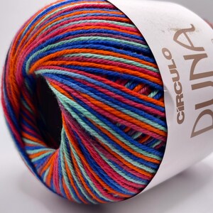 May include: A vibrant ball of yarn with a multicolored pattern of blue, orange, pink, and green threads. The yarn is labeled "CIRCULO DUNA" and is 186 yards in length.