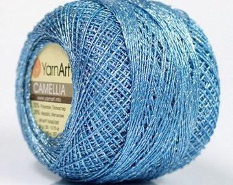May include: A skein of blue yarn with silver metallic thread. The label reads "YarnArt CAMELLIA" and includes information about the yarn's composition: 70% Polyester, 30% Metallic.