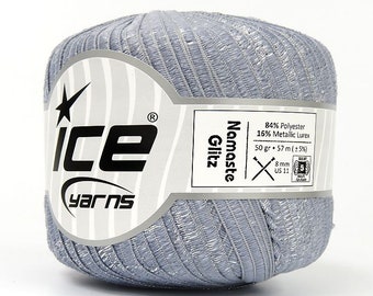 May include: A ball of Ice Yarns Namaste Glitz yarn in a light gray color with metallic silver threads. The label indicates the yarn is 84% polyester and 16% metallic lurex. The ball weighs 50 grams and is 57 meters long. The yarn is 8 mm and US 11.