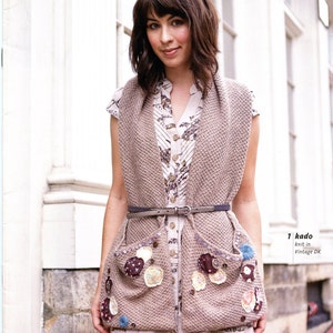 May include: A woman wearing a beige knitted vest with decorative fabric patches and a floral print dress. The vest has a belt and two large pockets. The text "Vintage DK™ & Vintage™" and "1 kado knit in Vintage DK" is visible in the image.