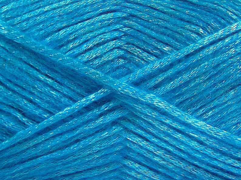 May include: Close-up of a skein of bright turquoise yarn. The yarn is soft and fluffy, with a slight sheen.