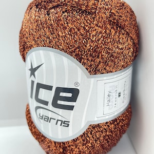 May include: A ball of copper-colored yarn with a silver glitter thread. The yarn is labeled "Ice Yarns" and "Halley 1.4 mm/US 11 Super Bulky".