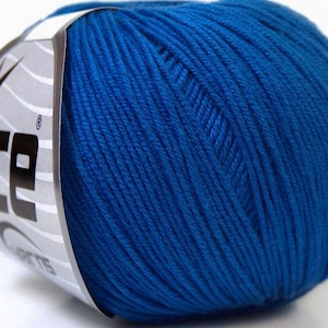 Op de afbeelding: Een bol felblauw garen met een label met de tekst "ice". Het garen is strak opgerold en toont afzonderlijke strengen. Het label heeft een sterontwerp en het woord "ice" in vette, zwarte letters.