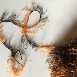 Peut inclure: Composition abstraite avec des brins de fil à franges noirs et orange. Le fil est disposé selon un motif fluide et organique sur fond blanc. Le contraste des couleurs et des textures crée un design visuellement intéressant.