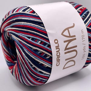 May include: A ball of Duna yarn with a white label. The yarn is a mix of red, white, navy blue, and light blue. The label reads "CIRCULO DUNA 186 yds / 170 m".