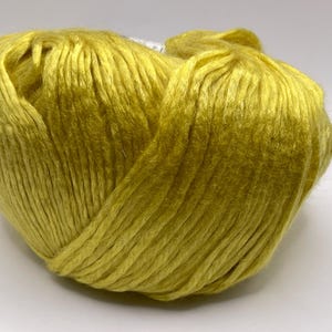 May include: A single ball of vibrant chartreuse yarn with a distinct sheen and smooth, continuous strands. The yarn is wound into a rounded, compact shape, showcasing the bright yellow-green color and the reflective quality of the fiber texture.