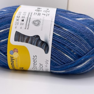 May include: A ball of blue yarn with white flecks, labeled "Streets Color" by henmayr. The label shows a sock design and washing instructions. The yarn is a wool-rich blend, 4-ply.