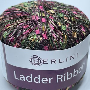 May include: A skein of multi-colored yarn with pink, green, and gold accents. The yarn is labeled "BERLINI Ladder Ribbon".