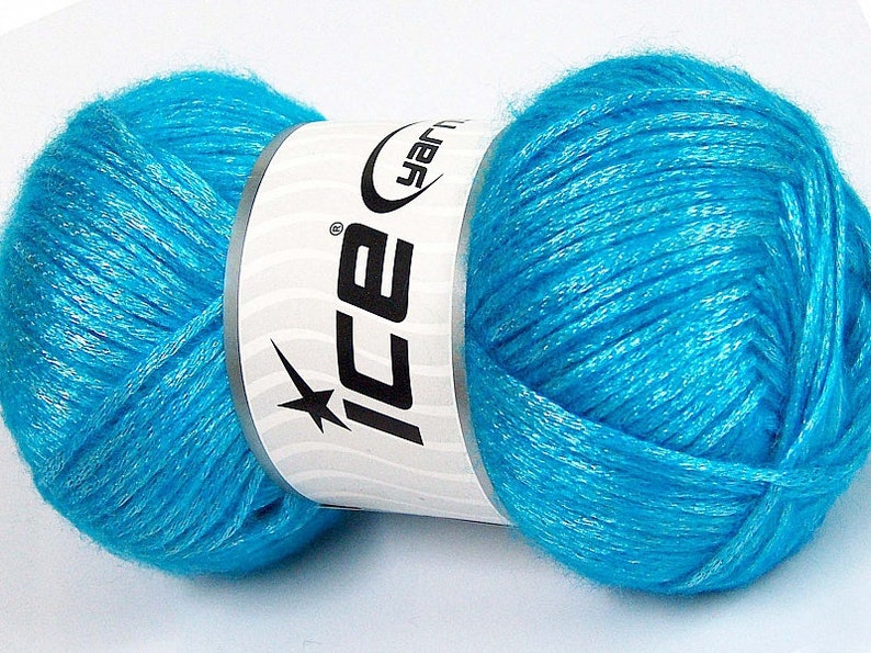 May include: A skein of turquoise blue yarn with silver glitter threads. The yarn is wrapped around a white label with the word "ICE" in black letters and a star.