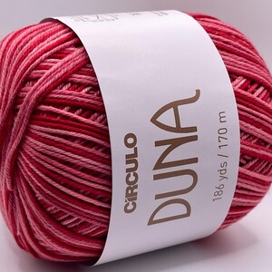 May include: A ball of red and pink yarn with a white label wrapped around it. The label reads "CIRCULO DUNA" in brown text, with "186 yds / 170 m" printed below. The yarn is a gradient of red and pink.