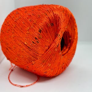 May include: A ball of orange yarn with sequins woven into the yarn.