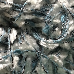 May include: Close-up of a blue and white yarn with a fuzzy texture. The yarn is made of a blend of fibres and has a black thread running through it.