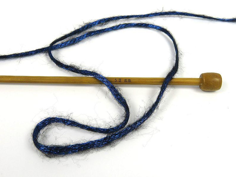 May include: A skein of blue yarn with a metallic sheen wrapped around a wooden knitting needle. The needle is labeled "5.0 mm".