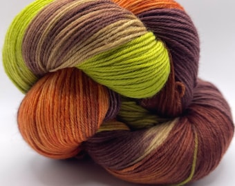 May include: A close-up of a skein of yarn in a variety of colors. The yarn is a mix of orange, green, brown, and purple. The yarn is tightly wound and appears soft. The yarn is likely used for knitting or crocheting.