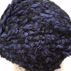 May include: A close-up of a blue and black yarn ball. The yarn is textured and fluffy.