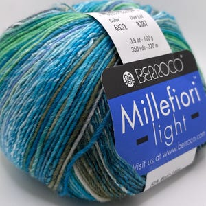 May include: A skein of Berroco Millefiori Light yarn in colourway 6832, 8387. The yarn is a blend of blue, green and white colours. The skein is 100 grams (3.5 ounces) and 320 metres (350 yards).