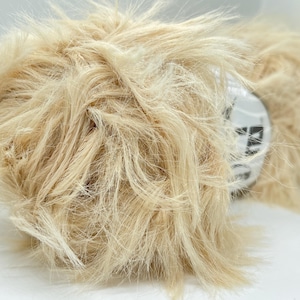 May include: A skein of light beige fluffy yarn. The yarn is soft and has a fuzzy texture.