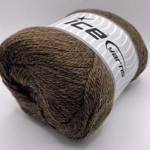 May include: A skein of brown yarn with a white and gray label wrapped around it. The label reads "ICE yarns" in a stylized font. The yarn appears soft and is a medium brown color.