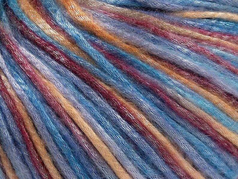 May include: A multi-colored yarn featuring a blend of vibrant blue, deep burgundy, and warm golden-tan strands. The fibers have a subtle sheen and a slightly fuzzy texture, arranged in parallel diagonal lines that create a rich, variegated appearance.