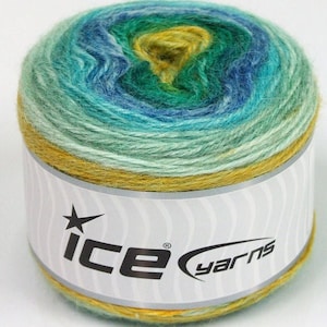 Può includere: Un gomitolo di filato in un gradiente di blu, verde e giallo. Il filato è avvolto attorno a un'etichetta bianca con il testo "ICE yarns" stampato su di essa.