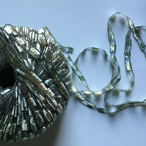 May include: A skein of green and silver yarn with a matching ribbon. The yarn is made of a thin, delicate material and has a subtle shimmer.