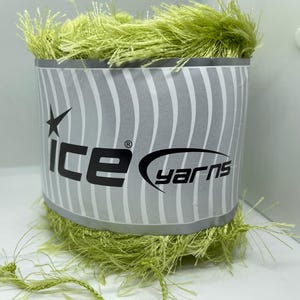 May include: A spool of lime green Ice Yarns with a textured, fringed appearance. The label features the brand name in black lettering with a star and a striped background.