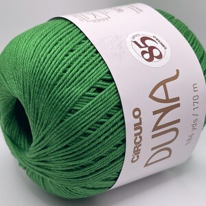 May include: A ball of bright green yarn with a white label wrapped around it. The label reads "CIRCULO DUNA" and "186 yds / 170 m". The yarn is tightly wound and appears soft, suitable for various knitting and crochet projects.