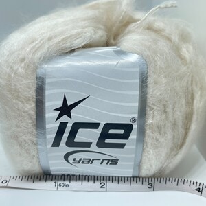 May include: A skein of off-white yarn with a label that says "Ice Yarns" and a star logo. The yarn is about 3 inches in diameter.