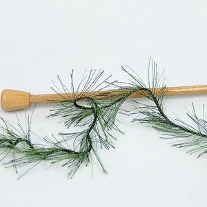 May include: Green and black fuzzy trim with a wooden dowel. The trim is a type of yarn or ribbon that is used for crafts and decorations.