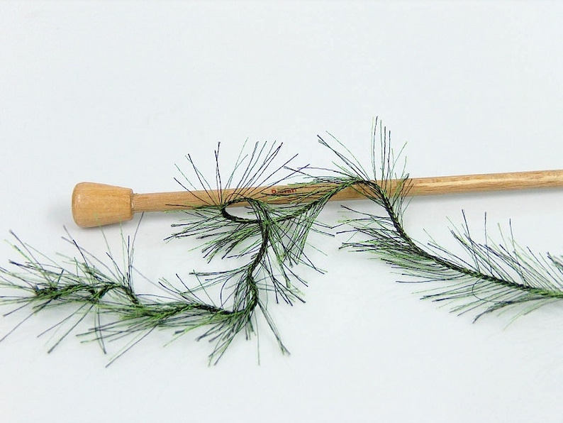 May include: Green and black fuzzy trim with a wooden dowel. The trim is a type of yarn or ribbon that is used for crafts and decorations.