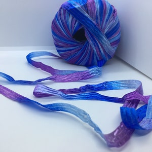 Op de afbeelding: Een bol ombre blauw en paars lint met een paar strengen lint die zijn losgemaakt.
