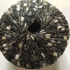 May include: A skein of black yarn with gold and silver metallic threads. The yarn is wound into a ball shape.