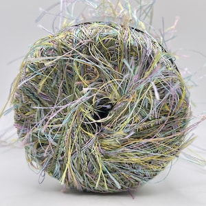 May include: A ball of colorful yarn with a mix of green, yellow, and purple threads. The yarn has a fuzzy texture and is wound around a dark core. Strands of yarn extend outward from the ball.
