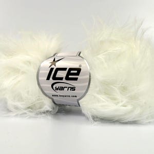 Puede incluir: Una madeja de hilo de piel sintética blanca con una etiqueta que dice "Ice Yarns" y "www.iceyarns.com".