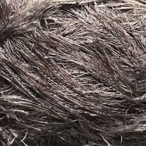 May include: Close-up of a bundle of gray, thin, and wispy fibers. The fibers are tightly packed together, creating a textured and fluffy appearance.