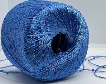 May include: A ball of blue yarn with silver sequins woven throughout. The yarn is wound into a tight ball with a hole in the centre.