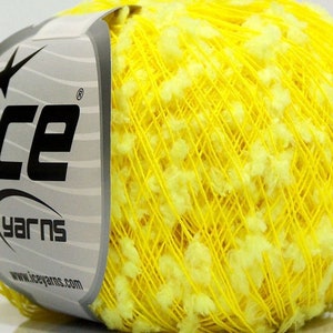 Puede incluir: Una bola de hilo amarillo con acentos blancos peludos. El hilo está etiquetado como "Ice Yarns" con la dirección del sitio web "www.iceyarns.com".