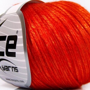 Puede incluir: Una madeja de hilo naranja vibrante, con la marca "ICE YARNS" visible en la etiqueta. El hilo parece suave y texturizado, ideal para proyectos de tejido o ganchillo. La etiqueta es blanca con rayas grises y texto negro.