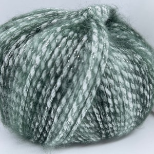 May include: A skein of green yarn with silver glitter throughout. The yarn is soft and fluffy.