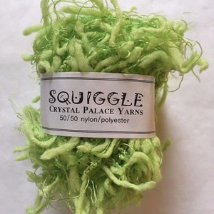 May include: A skein of light green yarn called "Squiggle" by Crystal Palace Yarns. The yarn is a 50/50 blend of nylon and polyester.