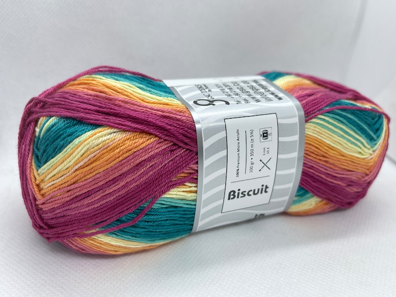 May include: A ball of multi-coloured yarn in shades of pink, orange, yellow, and teal. The yarn is labelled "Biscuit" and is 100% premium micro acrylic. The ball is 100 grams and 350 metres long.