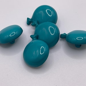 May include: A collection of five teal-colored, balloon-shaped buttons. Each button has a glossy finish and a small loop detail, resembling a balloon's tied end. The buttons are scattered on a white surface.