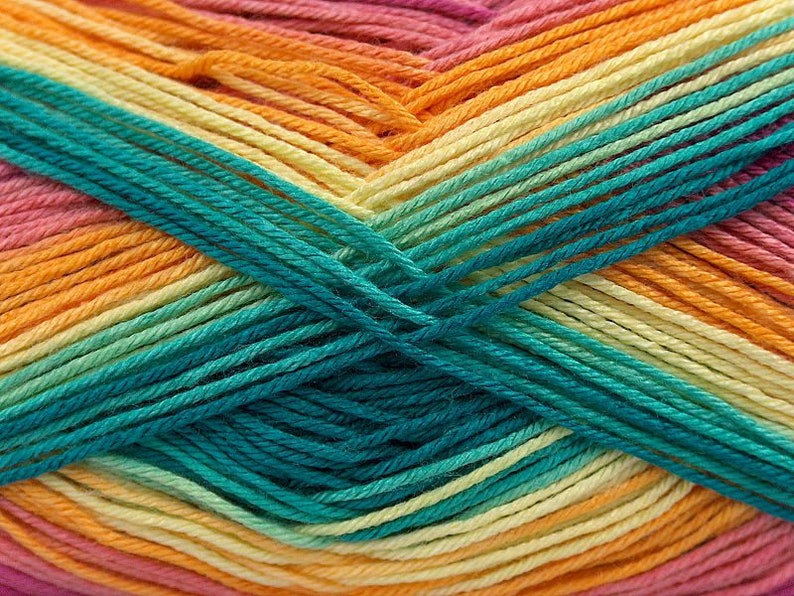 May include: Close-up of a ball of yarn with a gradient of orange, yellow, green, and pink colours. The yarn is made of soft, textured fibres and is perfect for knitting or crocheting.