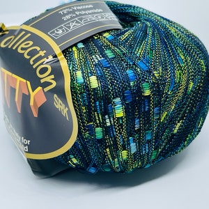 Może przedstawiać: Motka włóczki w niebiesko-zielono-żółtej kolorystyce z dodatkiem złotej nici metalicznej. Włóczka jest oznaczona jako "Collection SRK" i "72% Wiskoza 28% Poliamid".