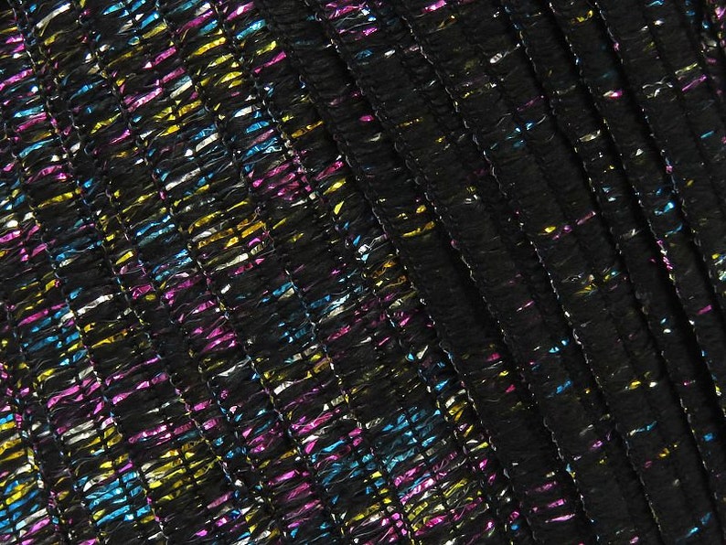 May include: Black fabric with a textured, woven pattern. The fabric has a metallic sheen with blue, pink, gold, and silver threads.