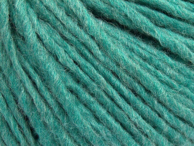 May include: Teal blue yarn with a fuzzy texture. The yarn is wound into a ball.