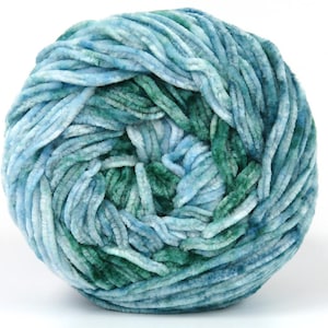 Könnte beinhalten: Ein Knäuel weiches, plüschiges Garn in Blau- und Grüntönen. Das Garn hat eine samtige Textur und ist eng gewickelt, wodurch eine dichte, runde Form entsteht. Ideal für Strick- oder Häkelprojekte.