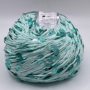 May include: A ball of light blue yarn with teal sequins. The yarn has a label that reads "Light" and lists the fiber content as 55% cotton and 45% other. This yarn is suitable for various crafting projects.